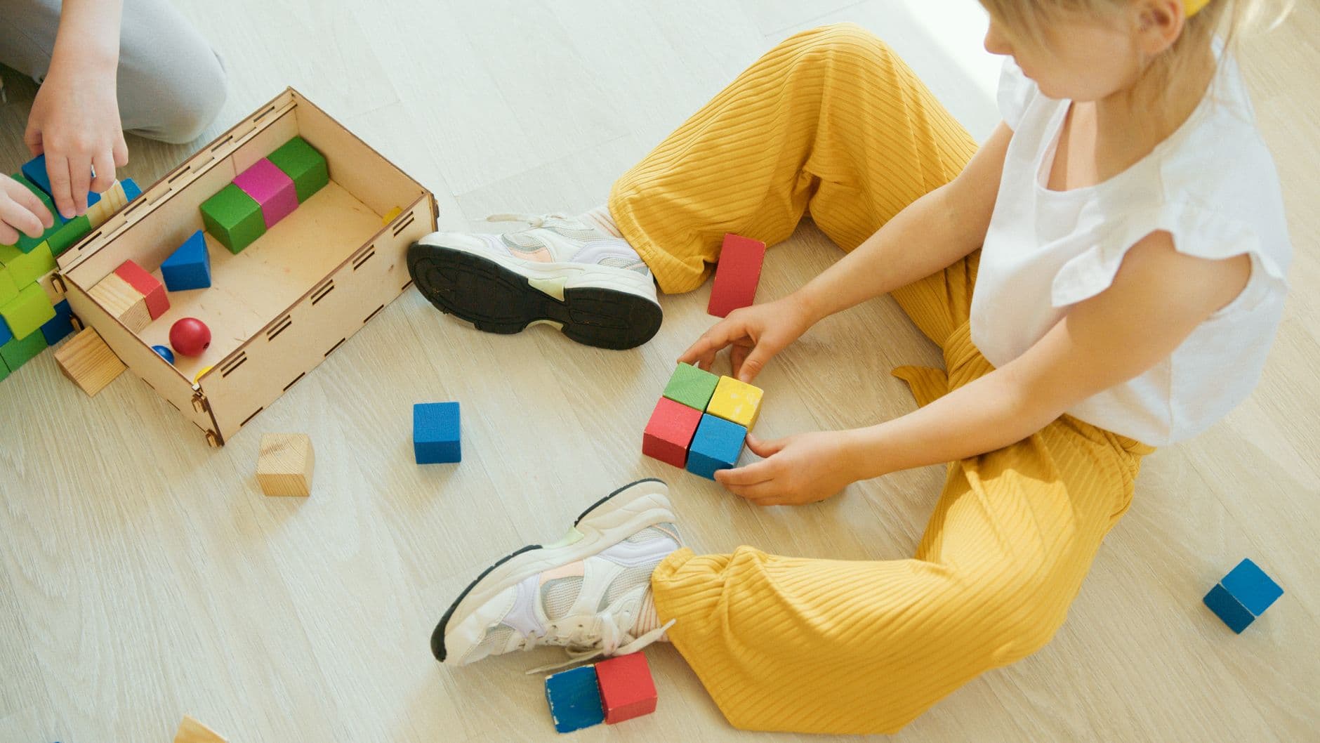 A therapist and a young child playing together with building blocks on the floor