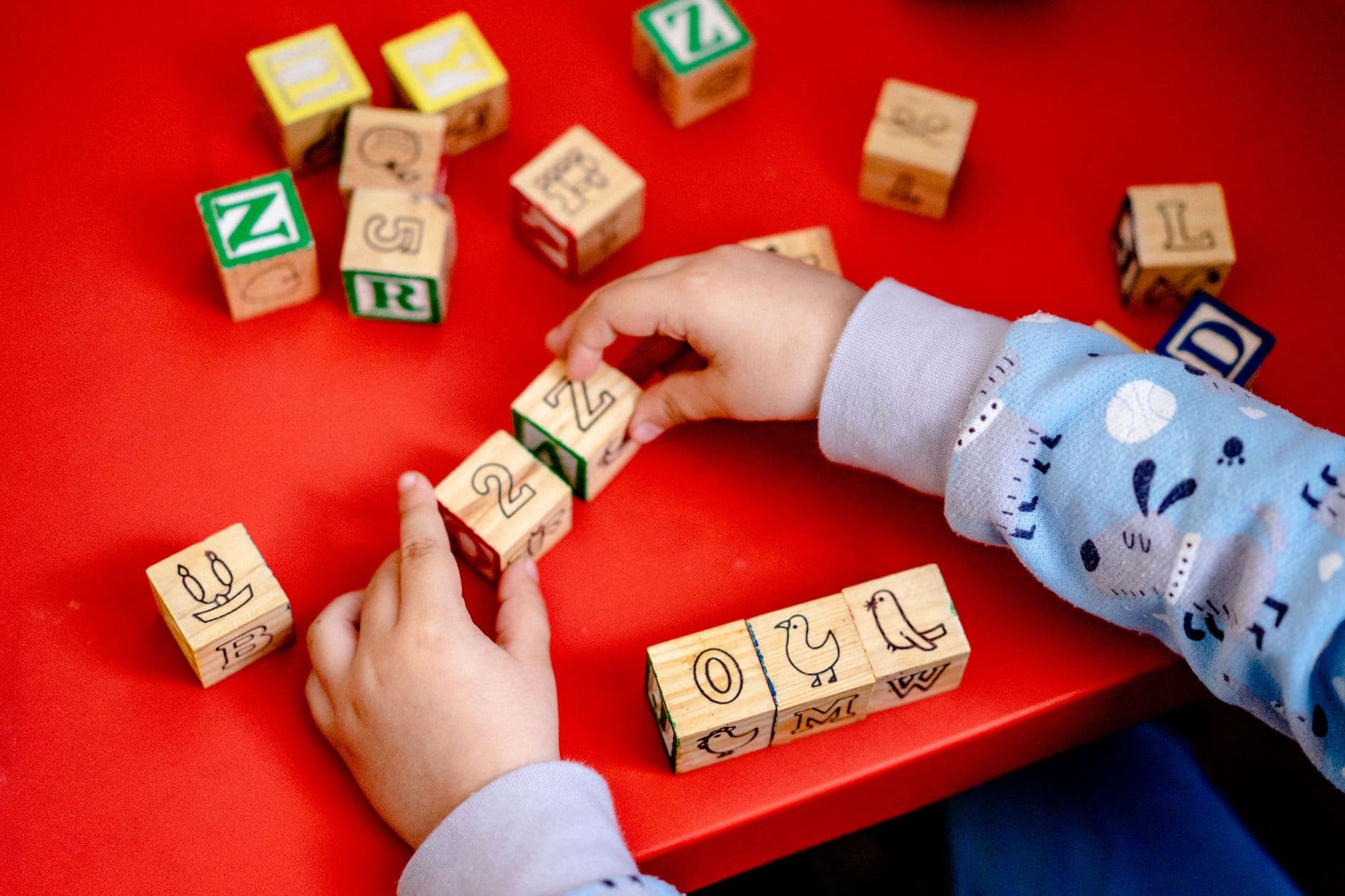 A child stacking colorful blocks while an adult gently helps