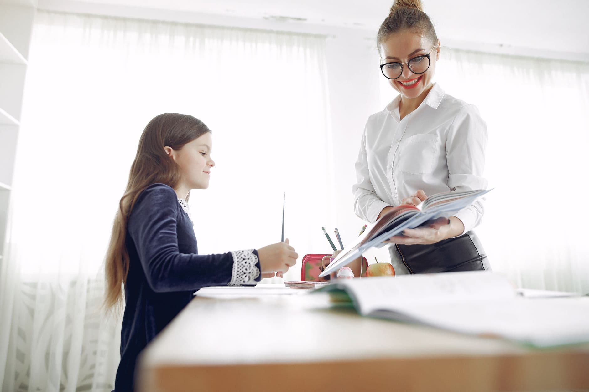 A teacher helping a young student at a desk