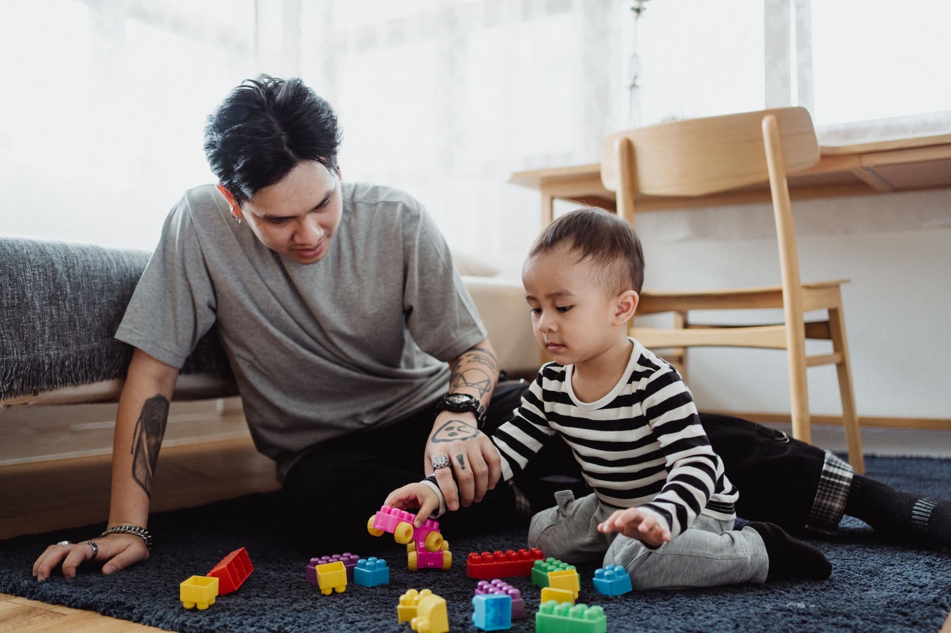 A parent and toddler playing with blocks together on the floor