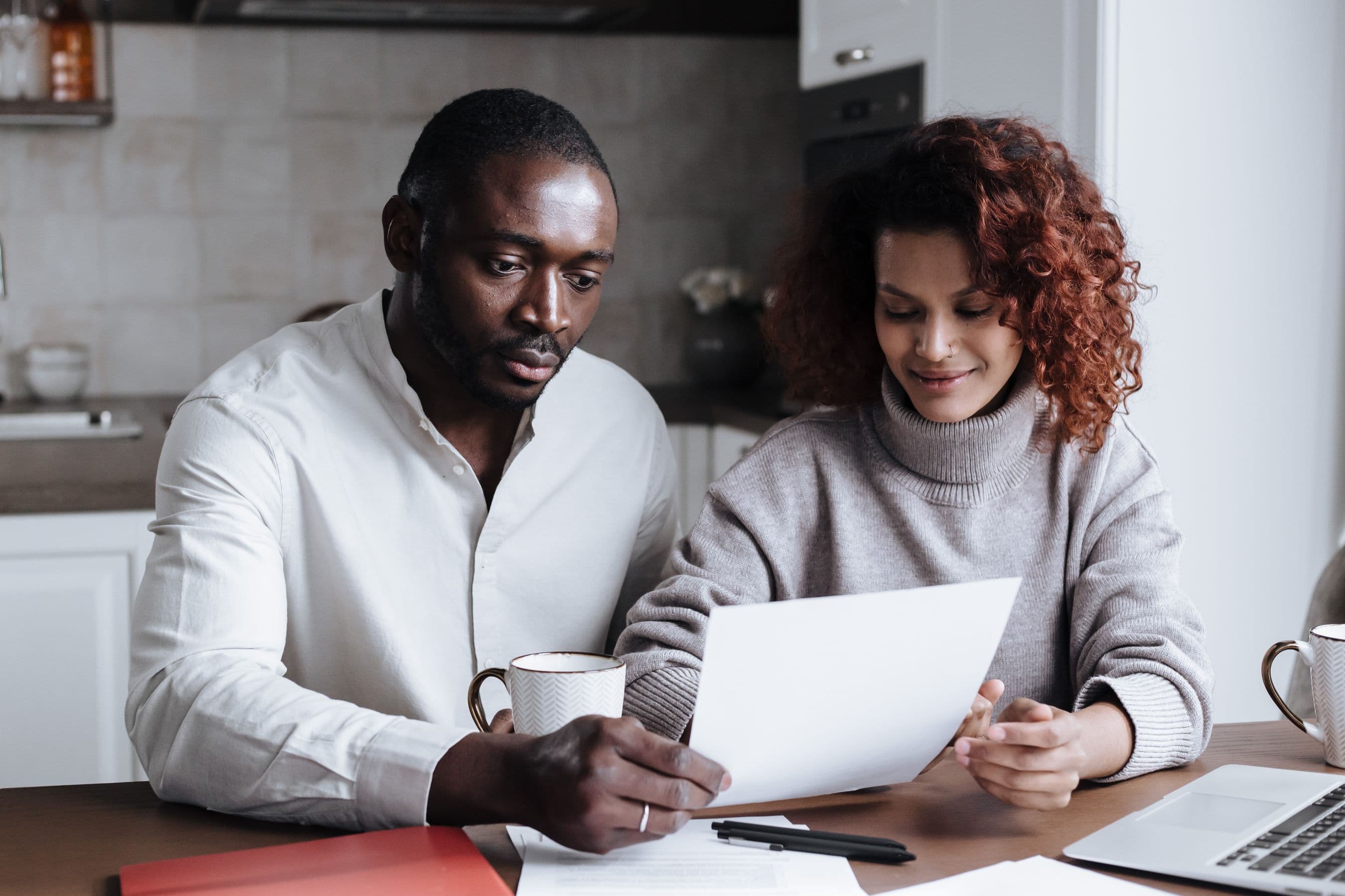 Two parents reviewing paperwork together at their kitchen table