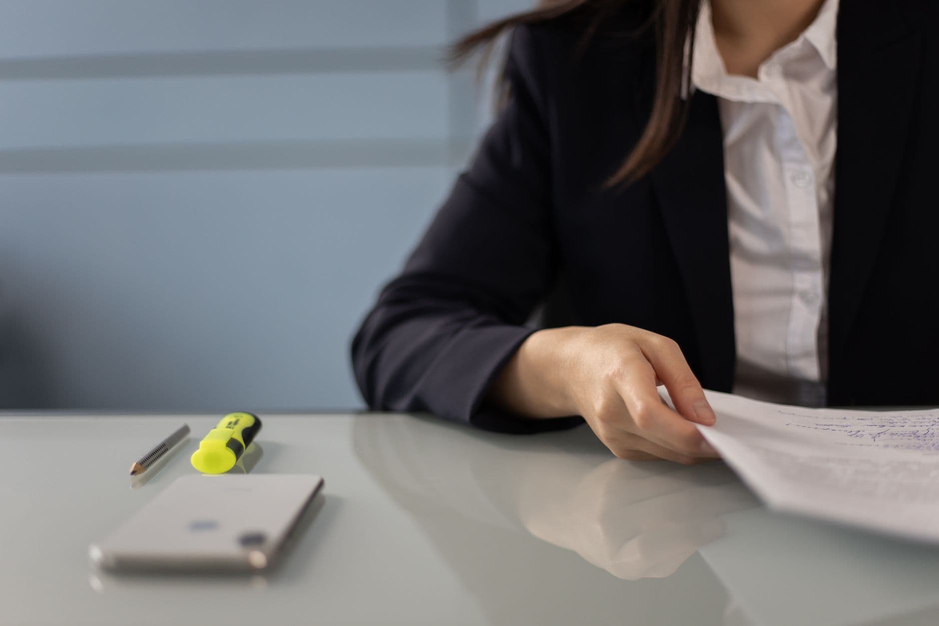 A person on the phone reviewing paperwork at a kitchen table