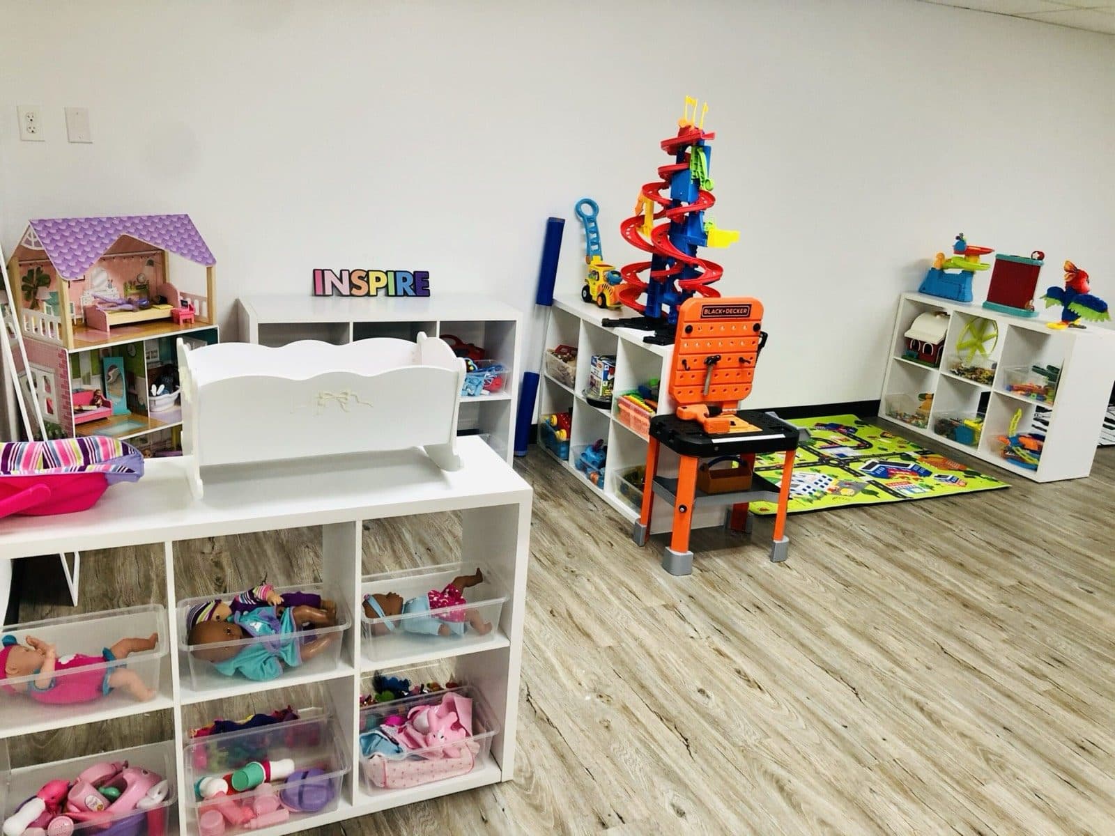A play and learning corner with a dollhouse, building toys, and an Inspire sign