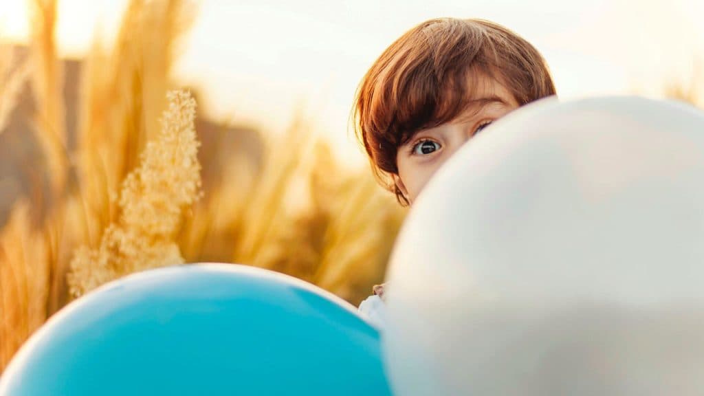 ABA kid playing behind balloons in Austin TX field