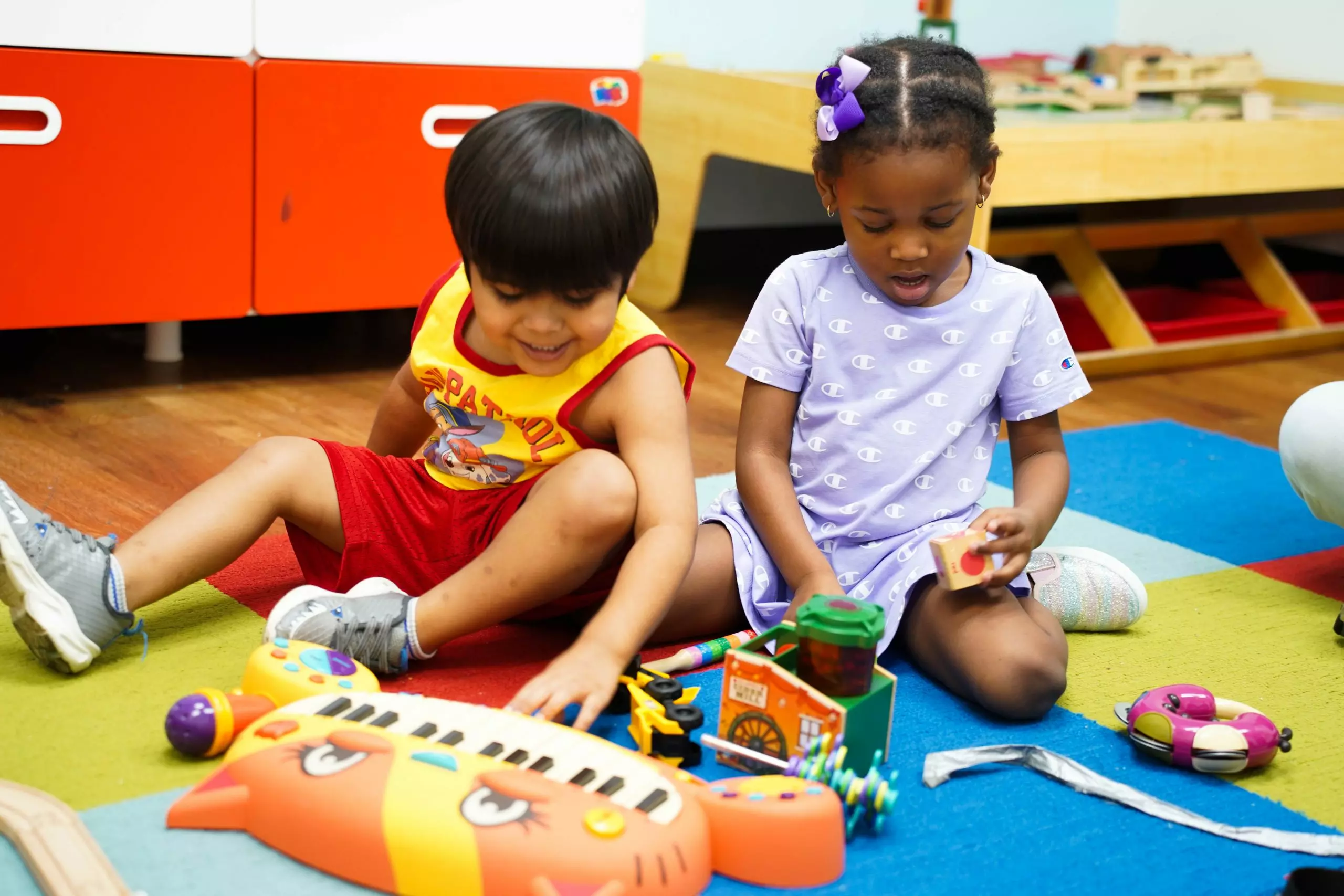 children sitting on carpet playing with toys