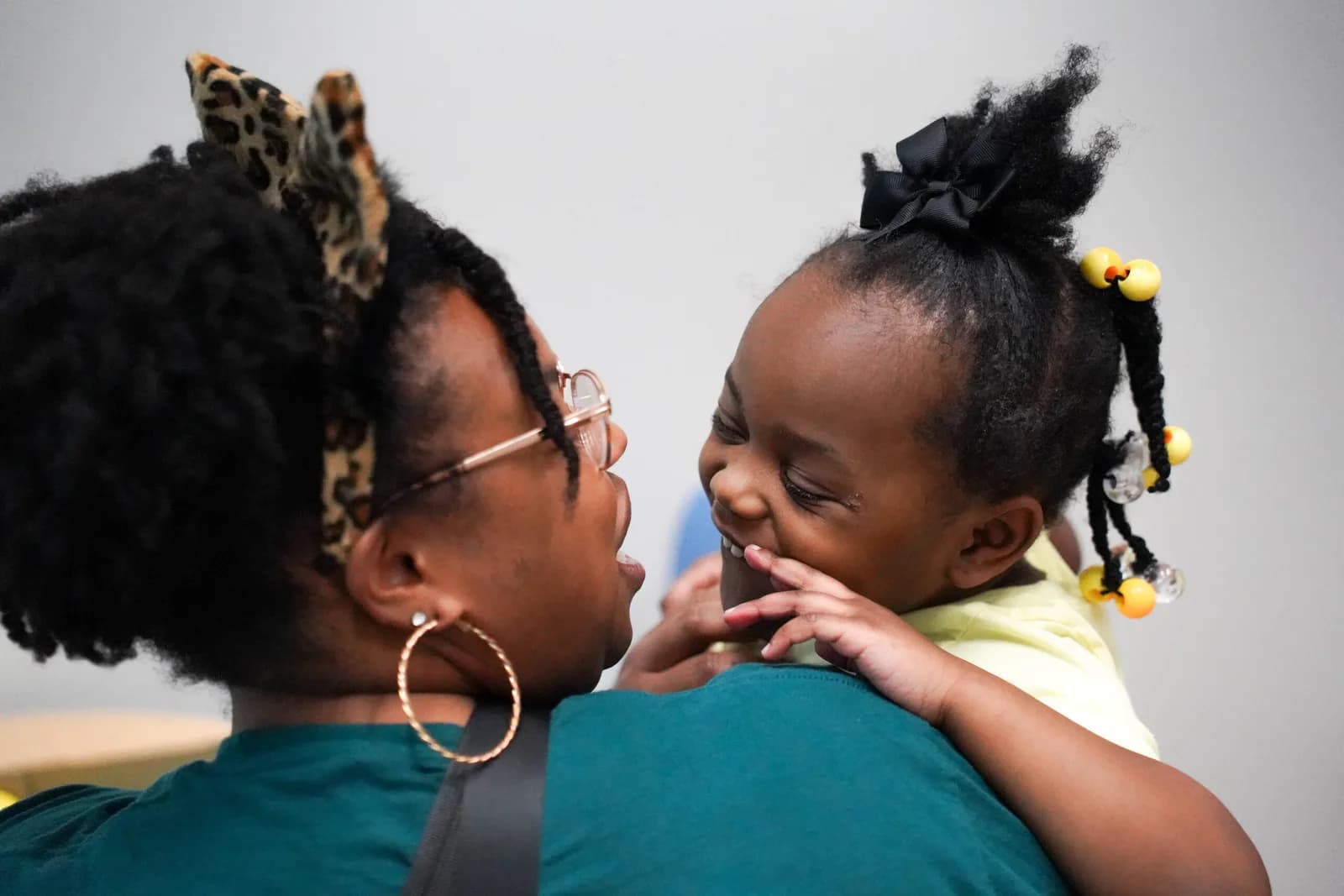 a woman wearing a leopard print headband is holding a little girl