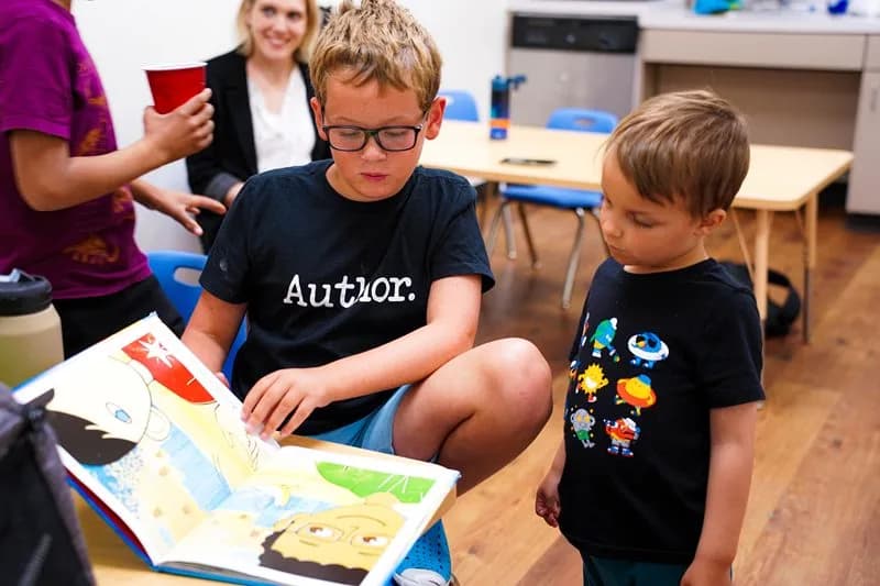a boy reading a book to another boy