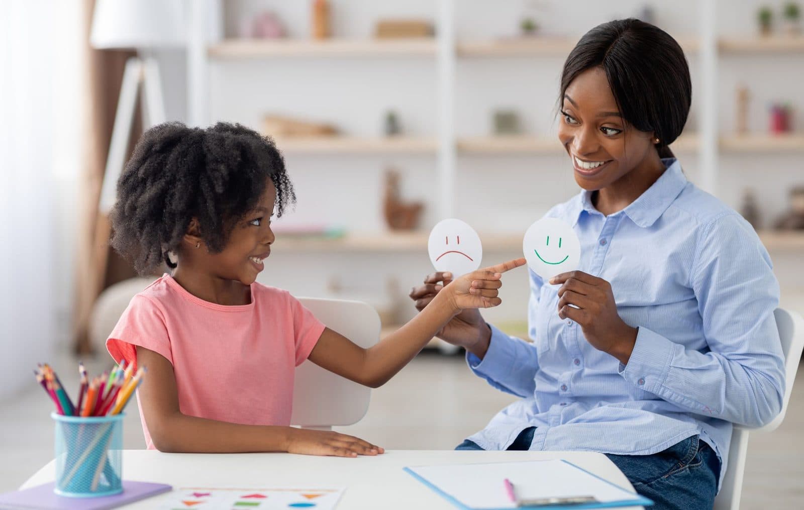 Therapist showing a smiling face card to a child in a light-filled office