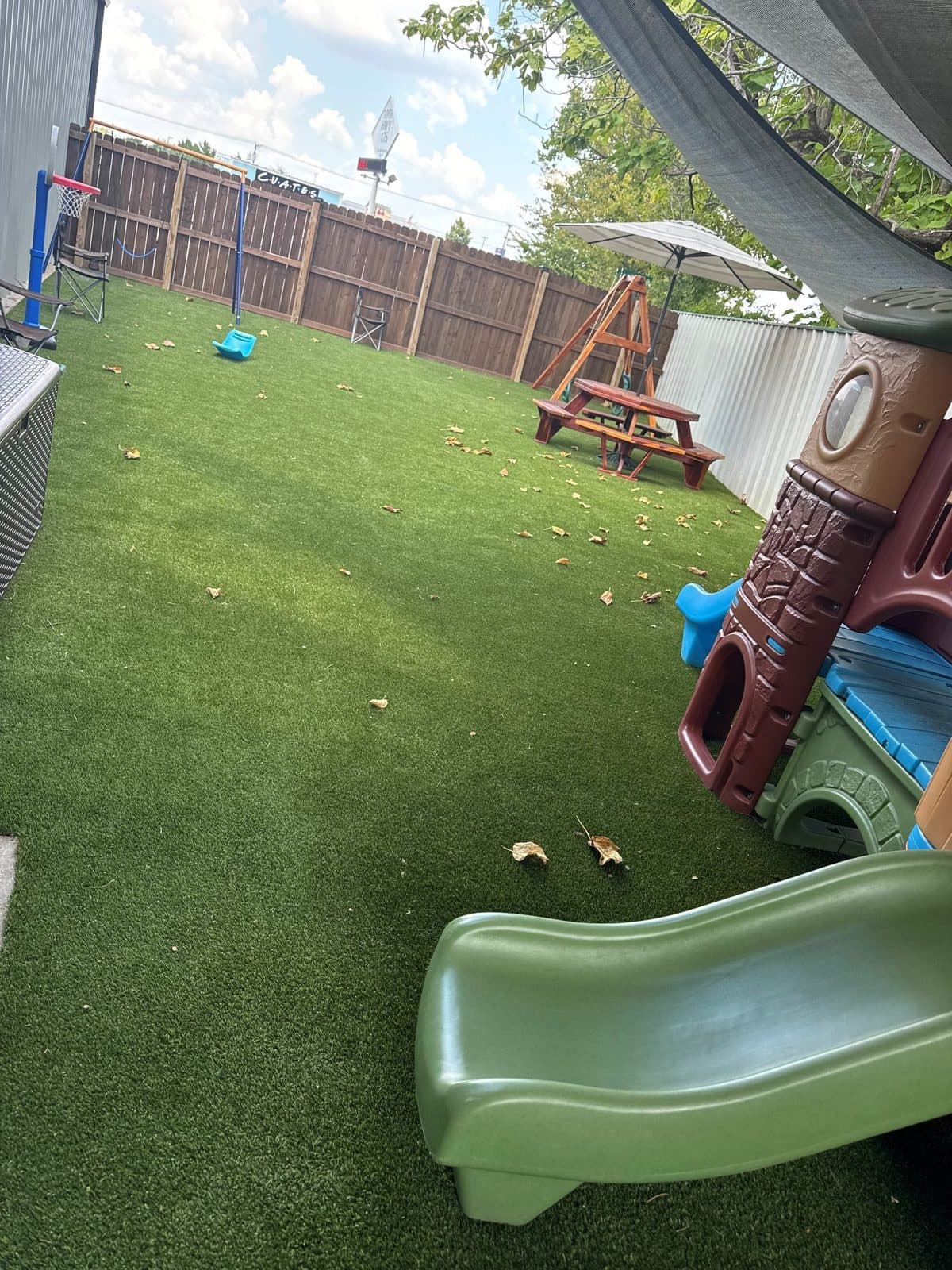 Playground with artificial turf, slide, picnic table, and fence