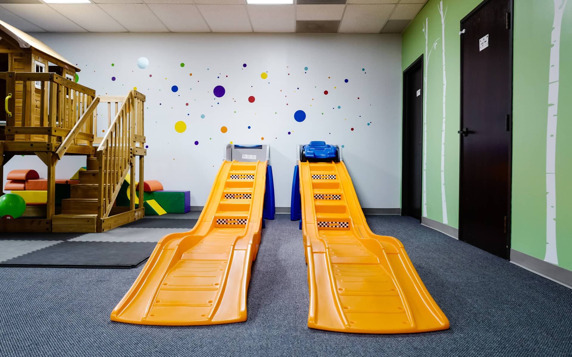 Indoor play area with slides and wooden house