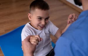 Therapist working with smiling child on floor exercises