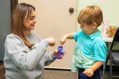 Woman and child exchanging fist bumps happily indoors.